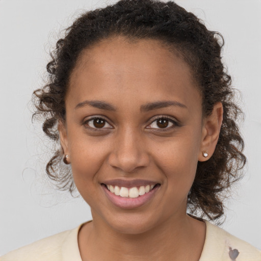 Joyful black young-adult female with long  brown hair and brown eyes