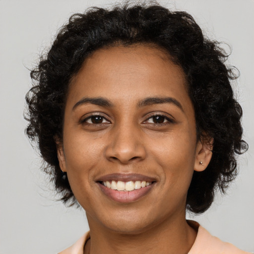 Joyful black young-adult female with long  brown hair and brown eyes