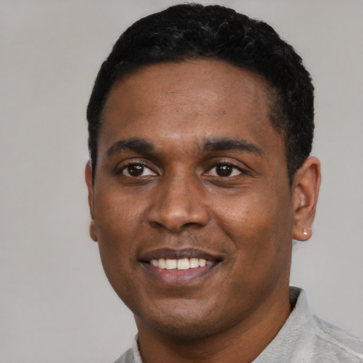 Joyful black young-adult male with short  black hair and brown eyes
