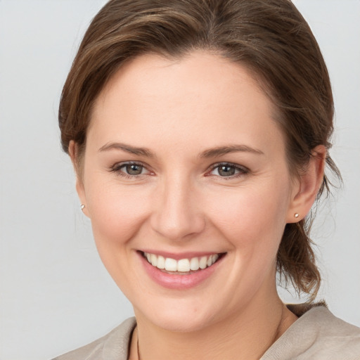 Joyful white young-adult female with medium  brown hair and grey eyes