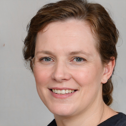 Joyful white adult female with medium  brown hair and blue eyes