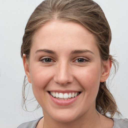 Joyful white young-adult female with medium  brown hair and grey eyes