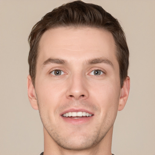 Joyful white young-adult male with short  brown hair and grey eyes