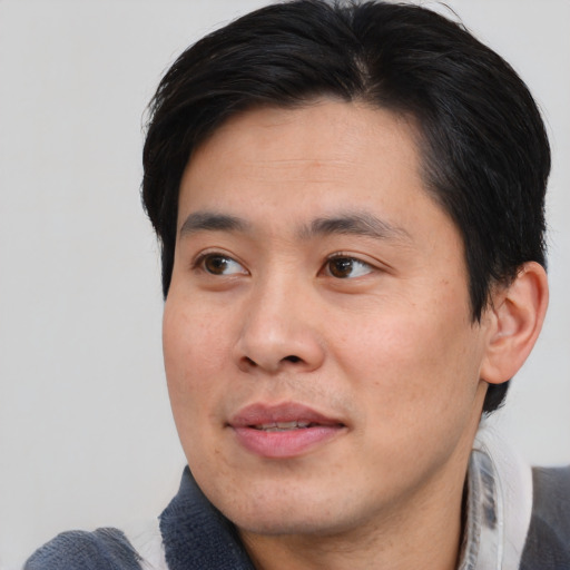 Joyful asian young-adult male with short  black hair and brown eyes