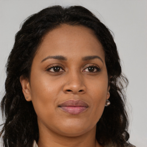 Joyful black young-adult female with long  brown hair and brown eyes