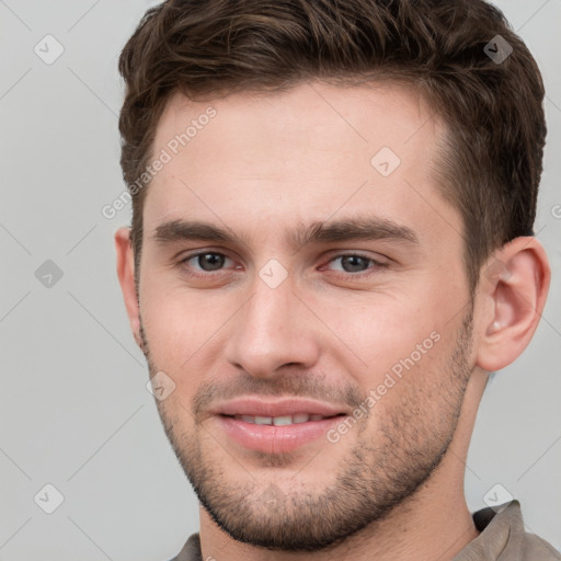 Joyful white young-adult male with short  brown hair and grey eyes