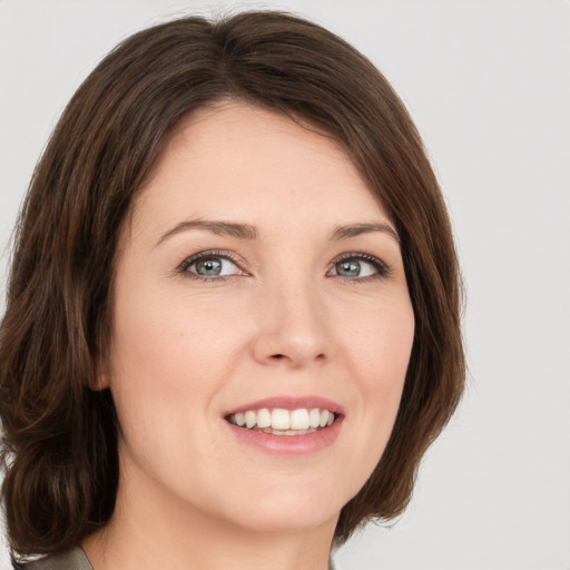 Joyful white young-adult female with medium  brown hair and green eyes