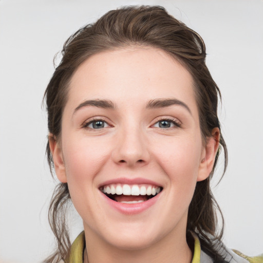 Joyful white young-adult female with medium  brown hair and grey eyes