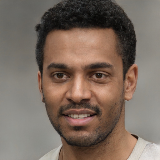 Joyful black young-adult male with short  black hair and brown eyes