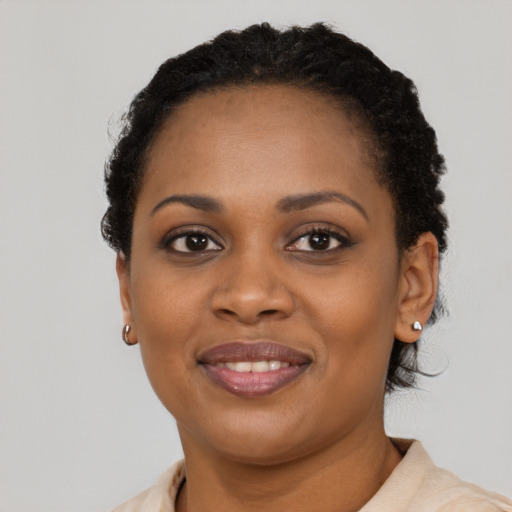 Joyful black young-adult female with short  black hair and brown eyes