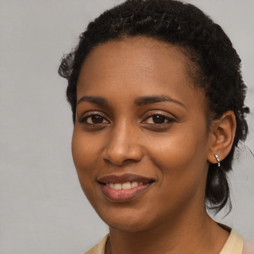Joyful black young-adult female with long  black hair and brown eyes