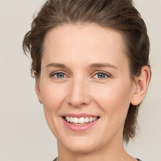 Joyful white young-adult female with medium  brown hair and grey eyes