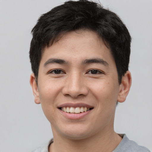 Joyful asian young-adult male with short  brown hair and brown eyes
