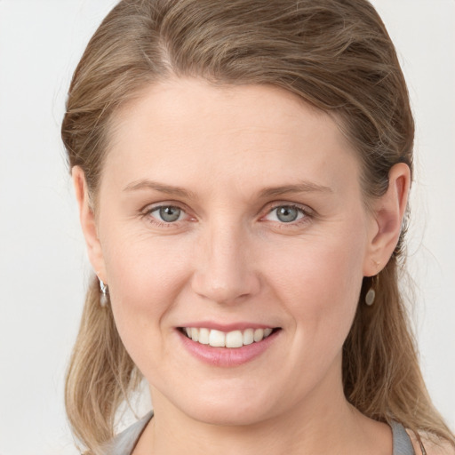 Joyful white young-adult female with long  brown hair and blue eyes