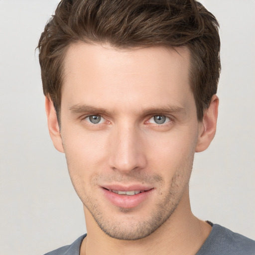 Joyful white young-adult male with short  brown hair and grey eyes