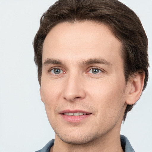 Joyful white young-adult male with short  brown hair and grey eyes