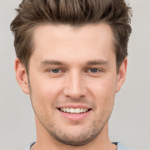 Joyful white young-adult male with short  brown hair and grey eyes