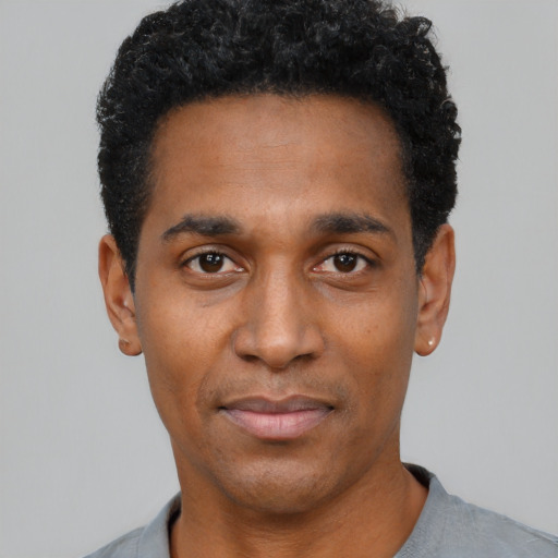 Joyful black young-adult male with short  black hair and brown eyes