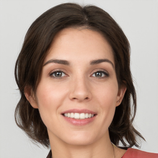 Joyful white young-adult female with medium  brown hair and grey eyes