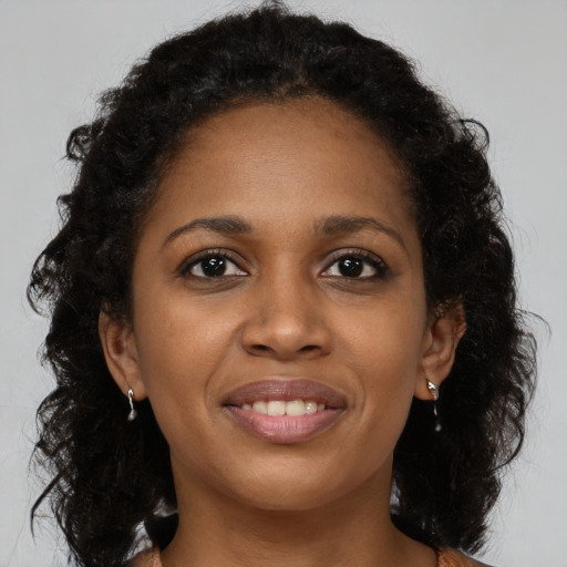 Joyful black young-adult female with long  brown hair and brown eyes