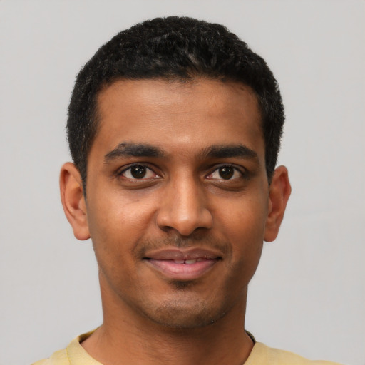 Joyful black young-adult male with short  black hair and brown eyes