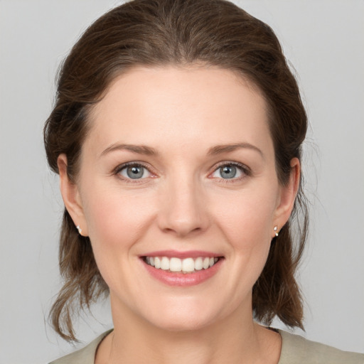 Joyful white young-adult female with medium  brown hair and grey eyes