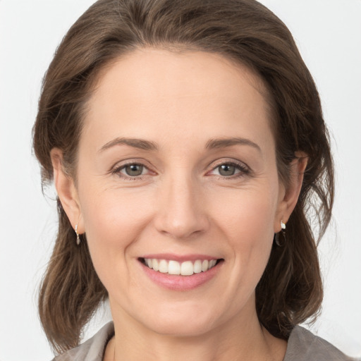 Joyful white young-adult female with medium  brown hair and grey eyes