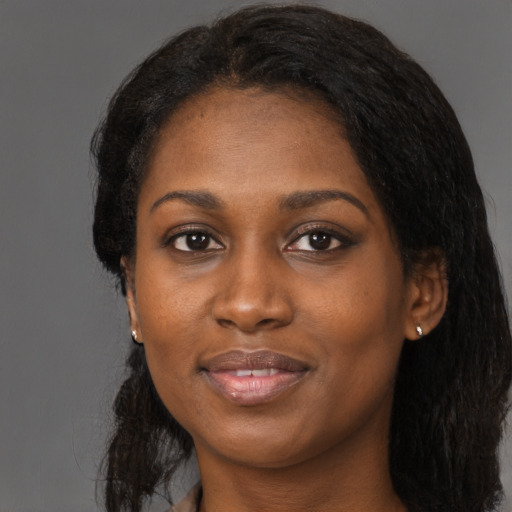 Joyful black young-adult female with long  black hair and brown eyes