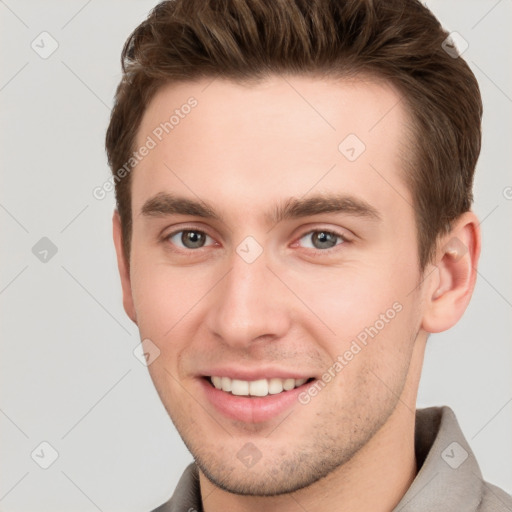 Joyful white young-adult male with short  brown hair and grey eyes