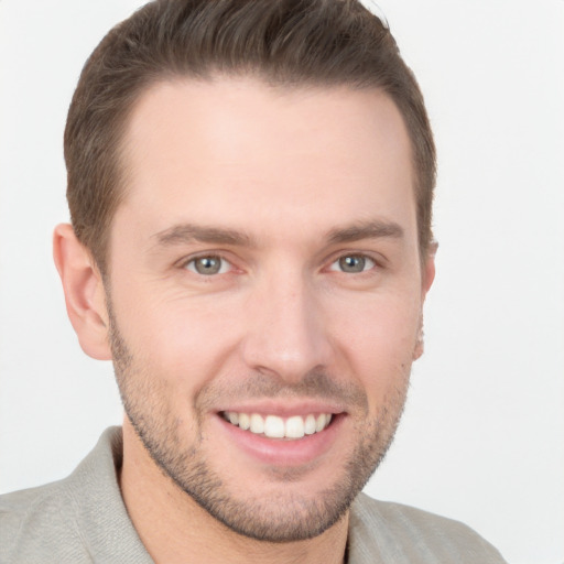 Joyful white young-adult male with short  brown hair and grey eyes