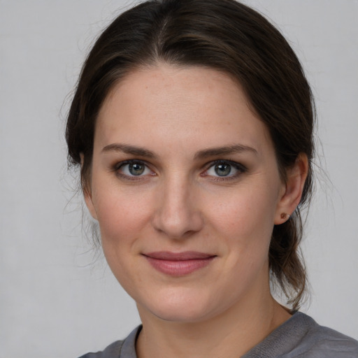 Joyful white young-adult female with medium  brown hair and grey eyes