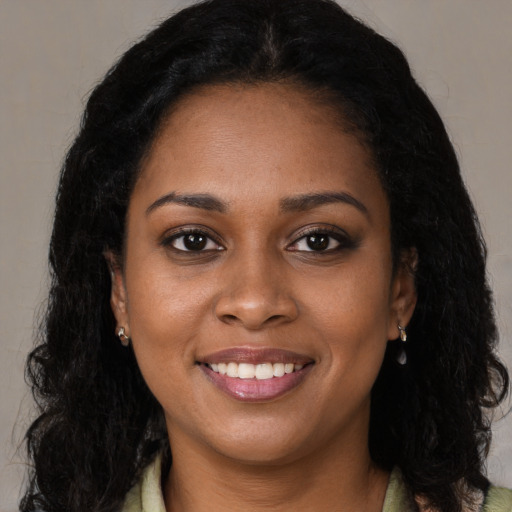 Joyful black young-adult female with long  brown hair and brown eyes