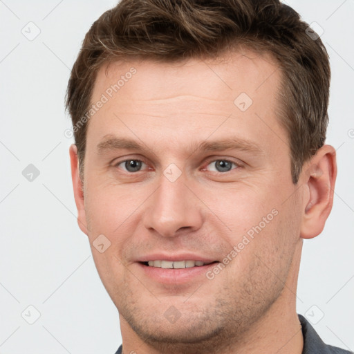 Joyful white young-adult male with short  brown hair and grey eyes