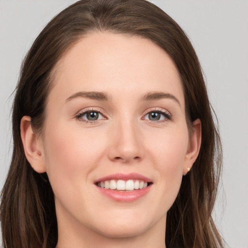 Joyful white young-adult female with long  brown hair and grey eyes