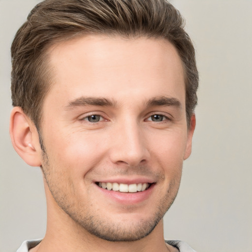 Joyful white young-adult male with short  brown hair and grey eyes