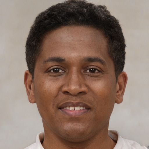 Joyful black young-adult male with short  brown hair and brown eyes