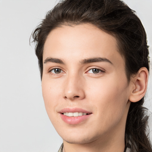 Joyful white young-adult male with long  brown hair and brown eyes