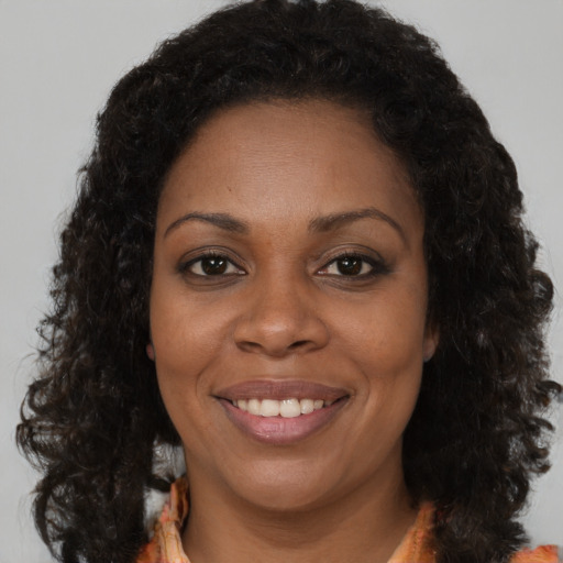 Joyful black adult female with long  brown hair and brown eyes