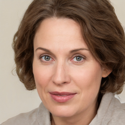 Joyful white adult female with medium  brown hair and green eyes