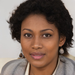 Joyful black young-adult female with long  brown hair and brown eyes