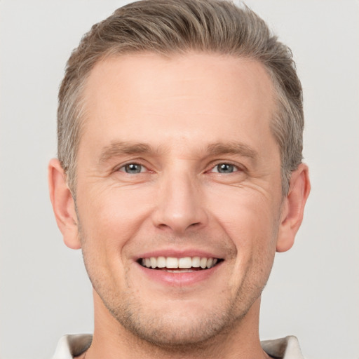 Joyful white adult male with short  brown hair and grey eyes