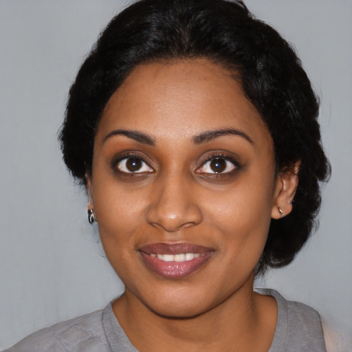 Joyful black young-adult female with short  black hair and brown eyes