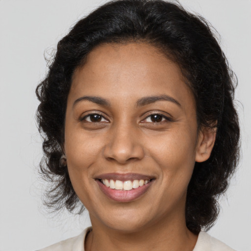 Joyful black young-adult female with long  brown hair and brown eyes