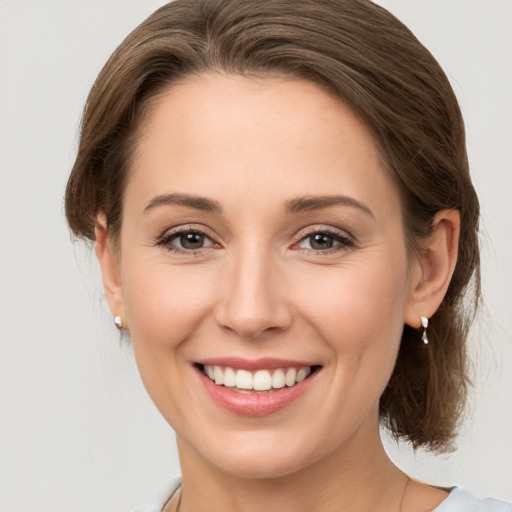 Joyful white young-adult female with medium  brown hair and grey eyes