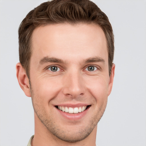 Joyful white young-adult male with short  brown hair and grey eyes