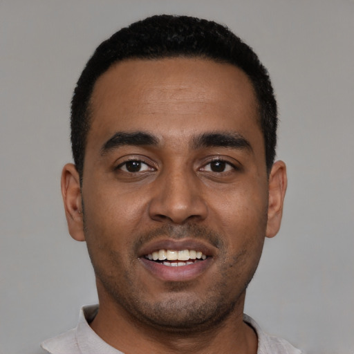 Joyful black young-adult male with short  black hair and brown eyes