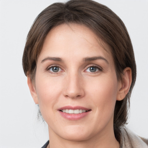 Joyful white young-adult female with medium  brown hair and grey eyes