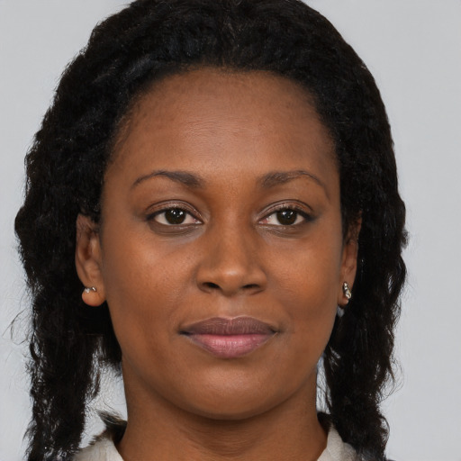 Joyful black young-adult female with long  brown hair and brown eyes