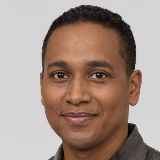 Joyful black young-adult male with short  black hair and brown eyes