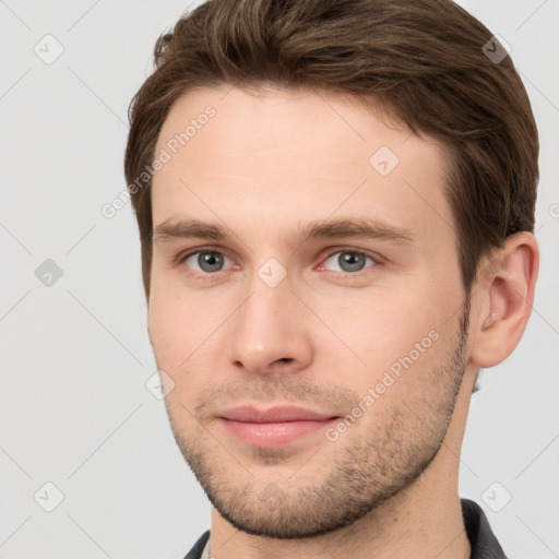 Joyful white young-adult male with short  brown hair and grey eyes